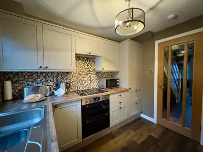 a kitchen with white cabinets and a black stove top oven at Cochrane House in Stirling