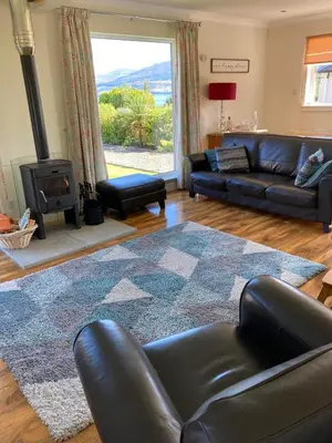 a living room with a leather couch and a fireplace at Holiday home, Carradale in Carradale