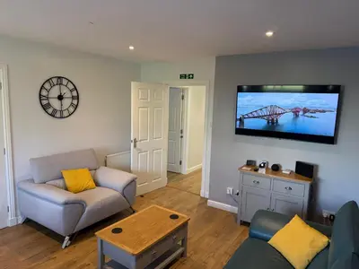 a living room with a couch and a tv on the wall at Dunfermline 2 Bed Flat Fully Furnished in Dunfermline
