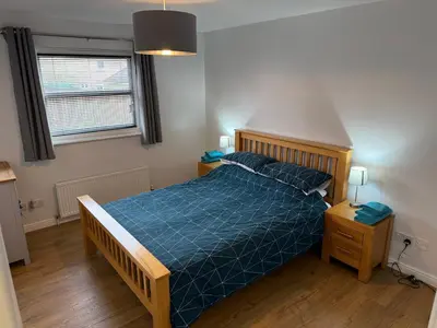 a bedroom with a bed with a blue comforter at Dunfermline 2 Bed Flat Fully Furnished in Dunfermline