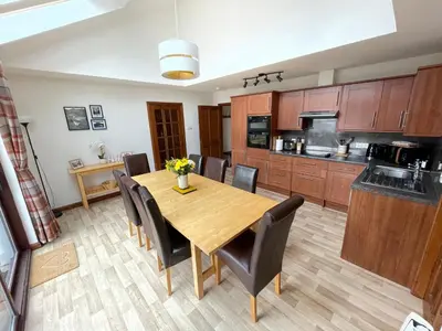 a kitchen and dining room with a wooden table and chairs at Old Springwell Croft in Onich