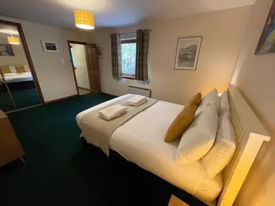 a bedroom with a large bed with white sheets and pillows at Old Springwell Croft in Onich
