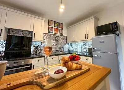 a kitchen with a table with a glass of wine and a bowl of fruit at Coorie Neuk in Cairnbaan
