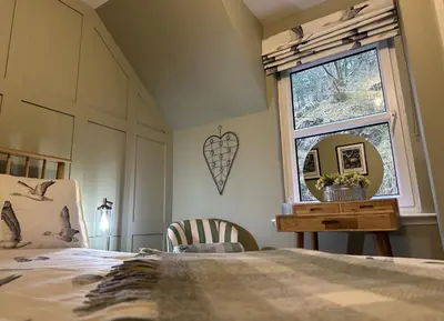 a bedroom with a bed and a window and a mirror at Coorie Neuk in Cairnbaan
