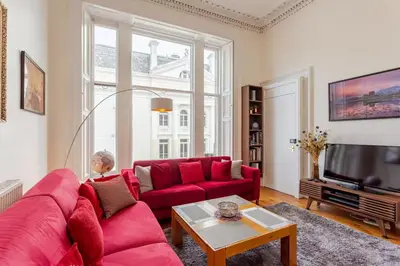 a living room with a red couch and a tv at Great Location! 2BD,2 Bath in Centre of Edinburgh in Edinburgh