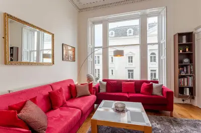 a red couch in a living room with a mirror at Great Location! 2BD,2 Bath in Centre of Edinburgh in Edinburgh