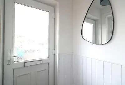 a hallway with a white door and a mirror at Signature - Thorn House in Coatbridge