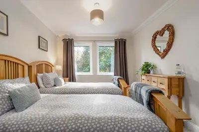 a bedroom with two beds and a mirror on the wall at Scenic Oaklodge with wood burner in Saint Fillans