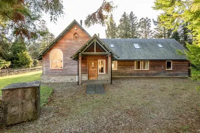 a wooden house with a large yard at Scenic Oaklodge with wood burner in Saint Fillans