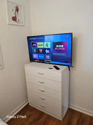 a flat screen tv on top of a white dresser at Double room available in Livingston