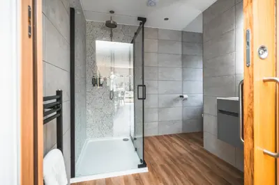 a bathroom with a shower with a glass door at Jackton Distillery Steadings in Busby