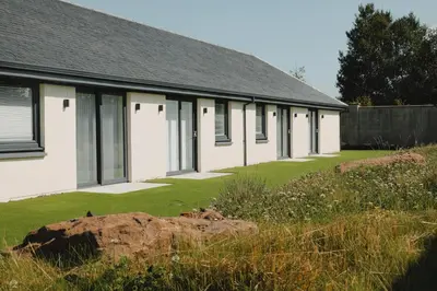 a row of white buildings with a yard at Jackton Distillery Steadings in Busby