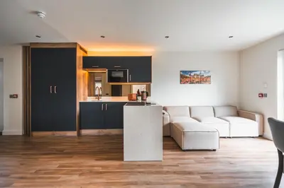 a living room with a white couch and a kitchen at Jackton Distillery Steadings in Busby
