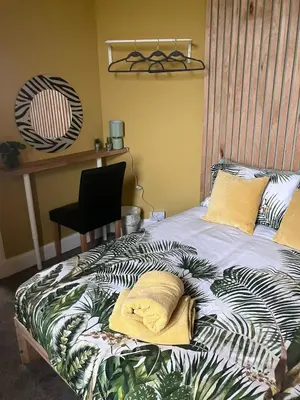 a bed with two pillows on it with a desk at The Gatehouse, 2 bedroom detached cottage in Beith