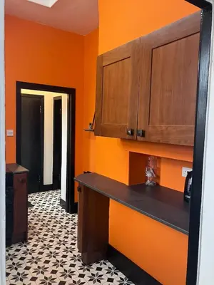 a kitchen with orange walls and a black counter top at The Gatehouse, 2 bedroom detached cottage in Beith