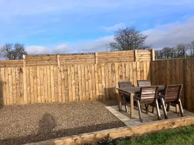 a table and chairs in front of a fence at The Gatehouse, 2 bedroom detached cottage in Beith