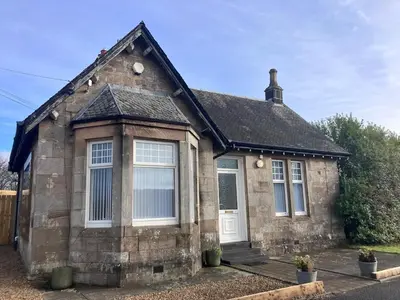 a small brick house with a white door at The Gatehouse, 2 bedroom detached cottage in Beith