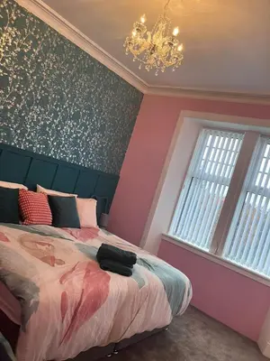 a bedroom with a bed and a chandelier at The Gatehouse, 2 bedroom detached cottage in Beith