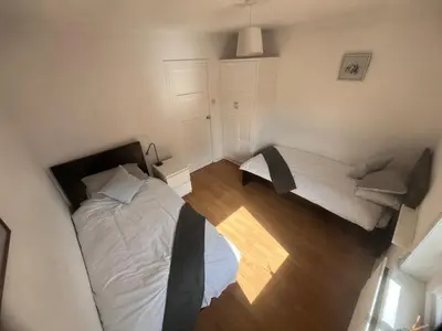 a small bedroom with two beds and a chair at Mitchell House in Bellshill