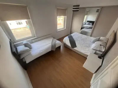 a small bedroom with two beds and a mirror at Mitchell House in Bellshill