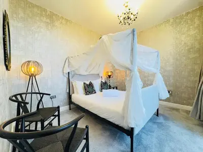 a bedroom with a white canopy bed with two chairs at Top Floor Getaway with Cozy Canopy Bed in Edinburgh