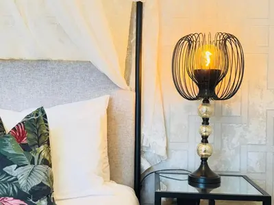 a lamp on a glass table next to a bed at Top Floor Getaway with Cozy Canopy Bed in Edinburgh