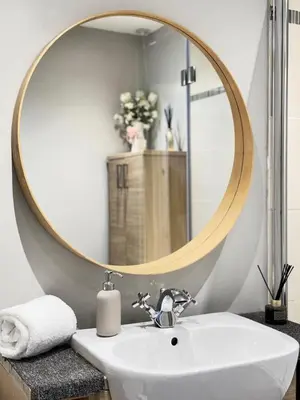 a bathroom with a round mirror above a sink at Top Floor Getaway with Cozy Canopy Bed in Edinburgh