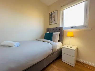 a small bedroom with a bed and a window at Sleek & Modern 2BR - Easy Access to City Centre in Glasgow