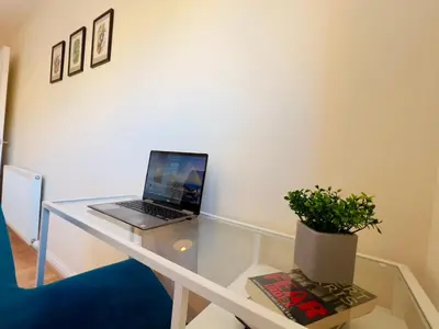 a laptop on a glass desk with a potted plant at Sleek & Modern 2BR - Easy Access to City Centre in Glasgow