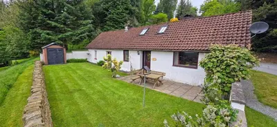a small white house with a picnic table in a yard at Ivy Tree Cottage in Morenish