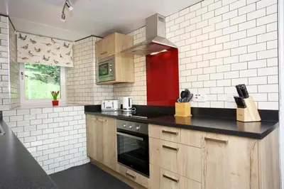 a kitchen with wooden cabinets and a counter top at Ivy Tree Cottage in Morenish