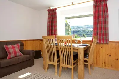a dining room with a table and chairs and a couch at Ivy Tree Cottage in Morenish