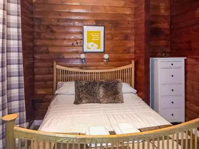 a bedroom with a bed in a log cabin at Grouse Lodge in Dunoon