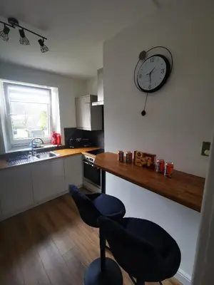 a kitchen with a clock on the wall and two chairs at Blanca apartment - free parking! in Oban