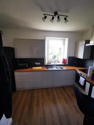 a kitchen with white cabinets and a sink and a window at Blanca apartment - free parking! in Oban