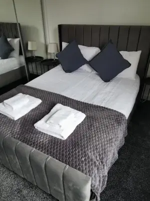a bed with white towels and blue pillows on it at Blanca apartment - free parking! in Oban