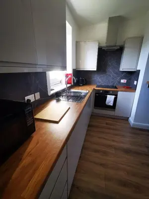 a kitchen with white cabinets and a wooden counter top at Blanca apartment - free parking! in Oban