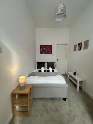 a bedroom with a bed and a table with a lamp at Cozy, modern flat in Govan in Glasgow