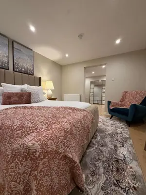 a bedroom with a large bed and a chair at Home away from home in Glasgow - Free Street Parking in Mansewood