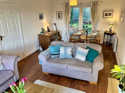 a living room with two couches and a table at Cosy Karibu cottage with stunning canal views in Cairnbaan