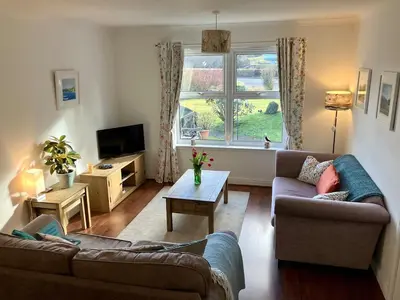 a living room with two couches and a window at Cosy Karibu cottage with stunning canal views in Cairnbaan