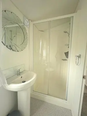 a white bathroom with a shower and a sink at The Linwood at StrathavonRentals in Girvan