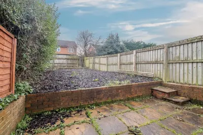 a backyard with a fence and a brick retaining wall at The Larky - Modern 2 Bed Cottage in Larkhall in Larkhall