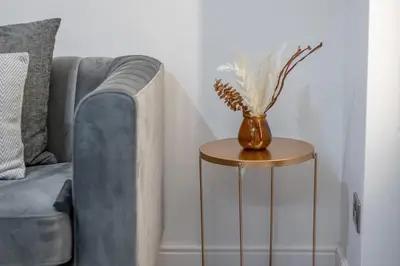 a vase on a side table next to a couch at The Larky - Modern 2 Bed Cottage in Larkhall in Larkhall