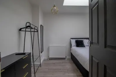 a bedroom with a bed and a dresser and a room at The Larky - Modern 2 Bed Cottage in Larkhall in Larkhall