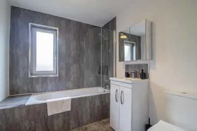 a bathroom with a bath tub and a sink at The Larky - Modern 2 Bed Cottage in Larkhall in Larkhall