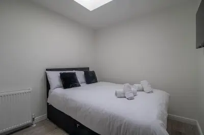 a bedroom with a bed with towels on it at The Larky - Modern 2 Bed Cottage in Larkhall in Larkhall