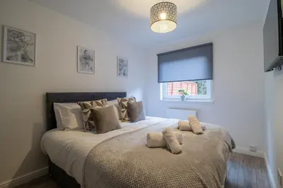 a bedroom with a large bed with pillows on it at The Larky - Modern 2 Bed Cottage in Larkhall in Larkhall