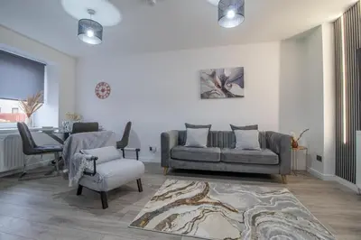 a living room with a couch and a chair at The Larky - Modern 2 Bed Cottage in Larkhall in Larkhall