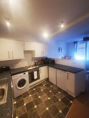 a kitchen with white cabinets and a washer and dryer at Stevenson Apartment in Oban City in Oban